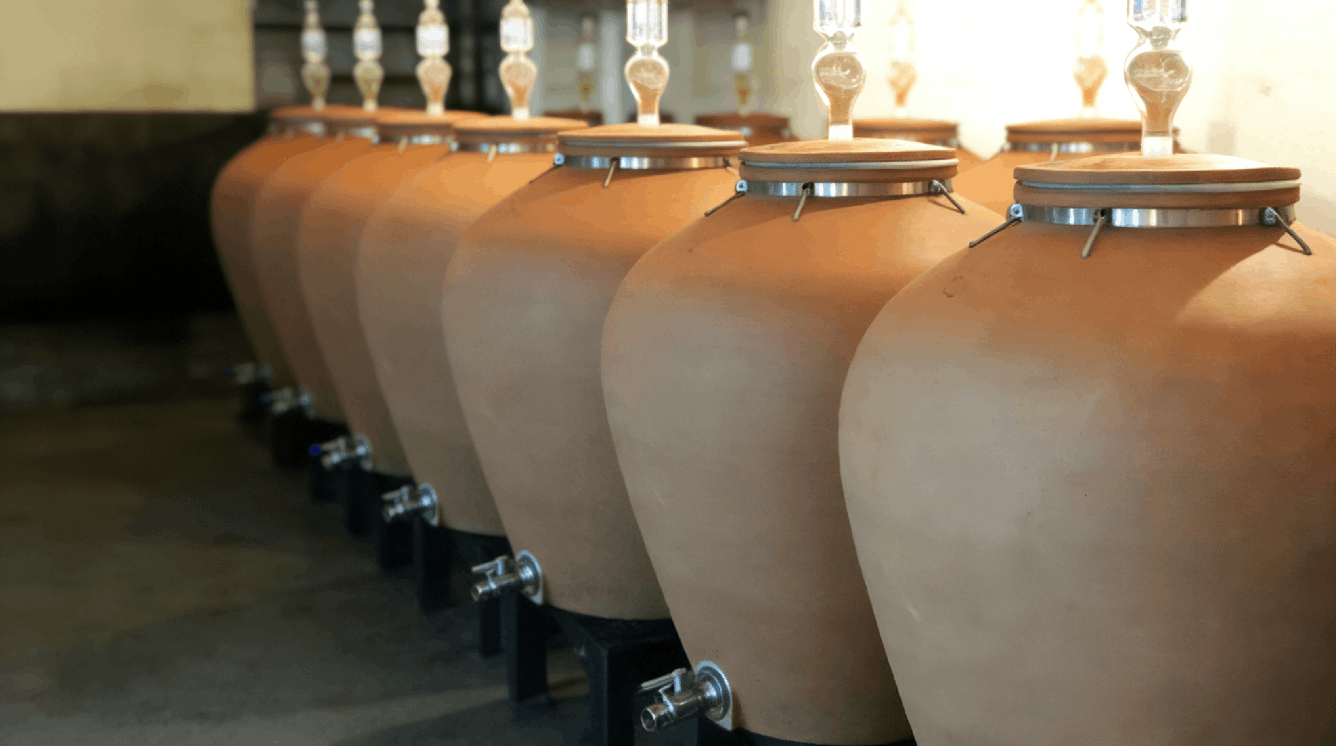 ancient amphora and modern wine amphora side by side, showing traditional clay fermentation vessels used in modern winemaking
